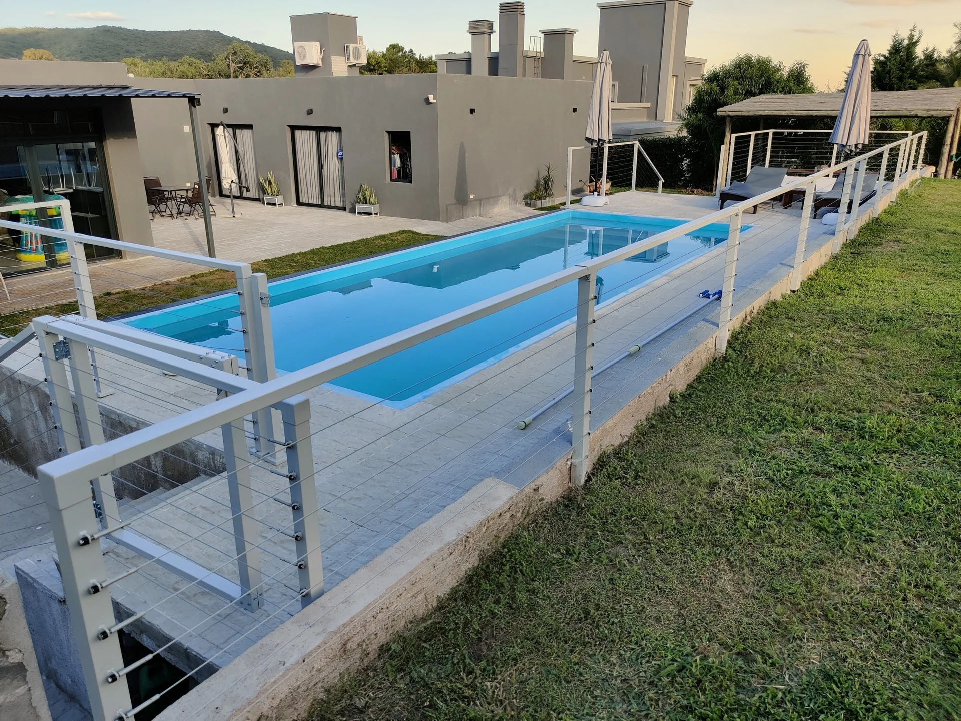 Barandas modulares blancas con cables de acero en el exterior de una vivienda.